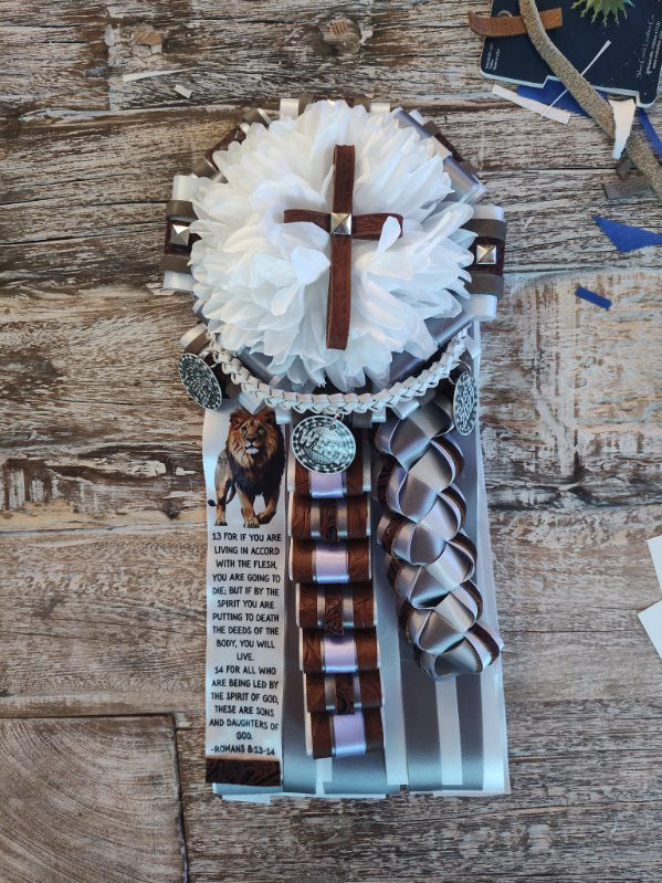 Brown, gray, and lavender homecoming garter with a white flower, wooden cross, lion charm, and Scripture verse ribbon