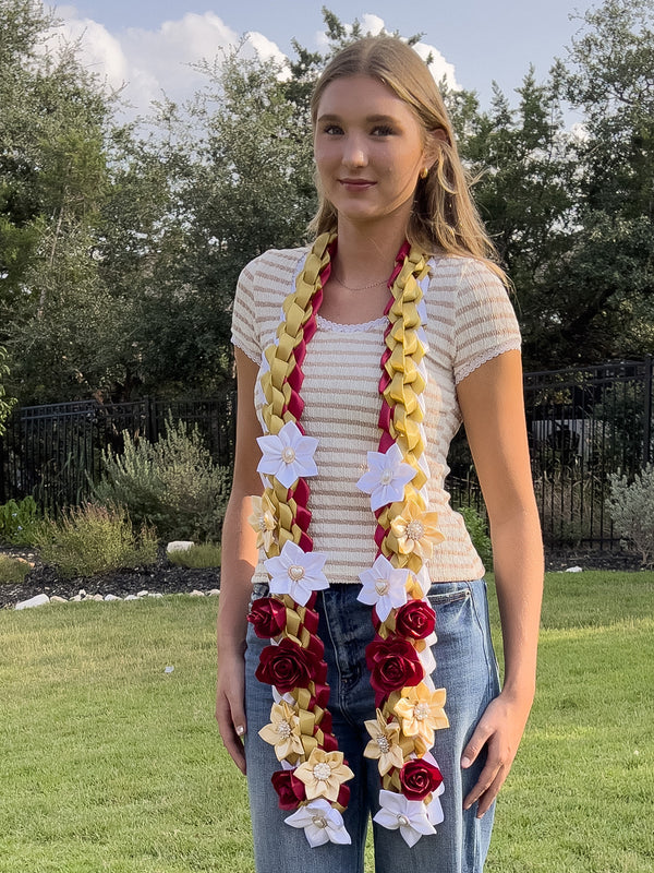 Graduate wearing a maroon, gold, and white braided ribbon lei with satin flowers