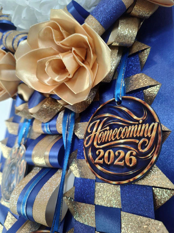 Close-up of a royal blue and gold homecoming mum with a gold satin rose and a Homecoming 2026 charm