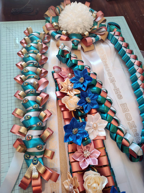 Teal, copper, and white homecoming mum in progress on the worktable, with blue and blush satin flowers