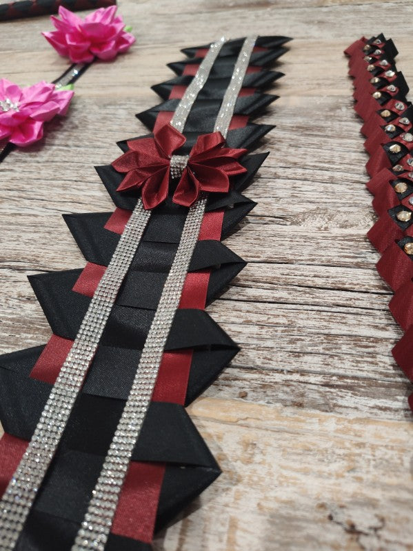 Maroon and black homecoming mum trim with a satin bow and rhinestone ribbon on a rustic table