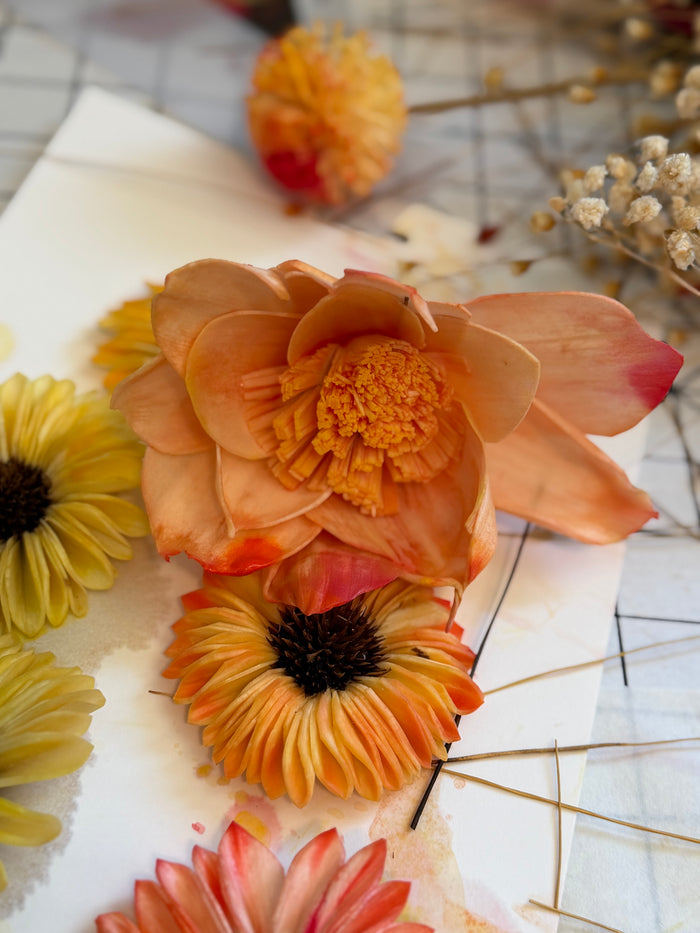 Peach, orange, and golden yellow flowers laid out on the worktable for a custom fall wreath